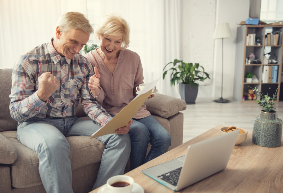 Elderly man and woman looking at a document with triumph