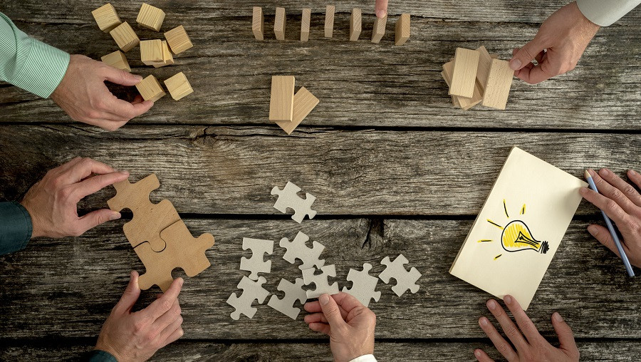 Several hands building a puzzle together seen from above