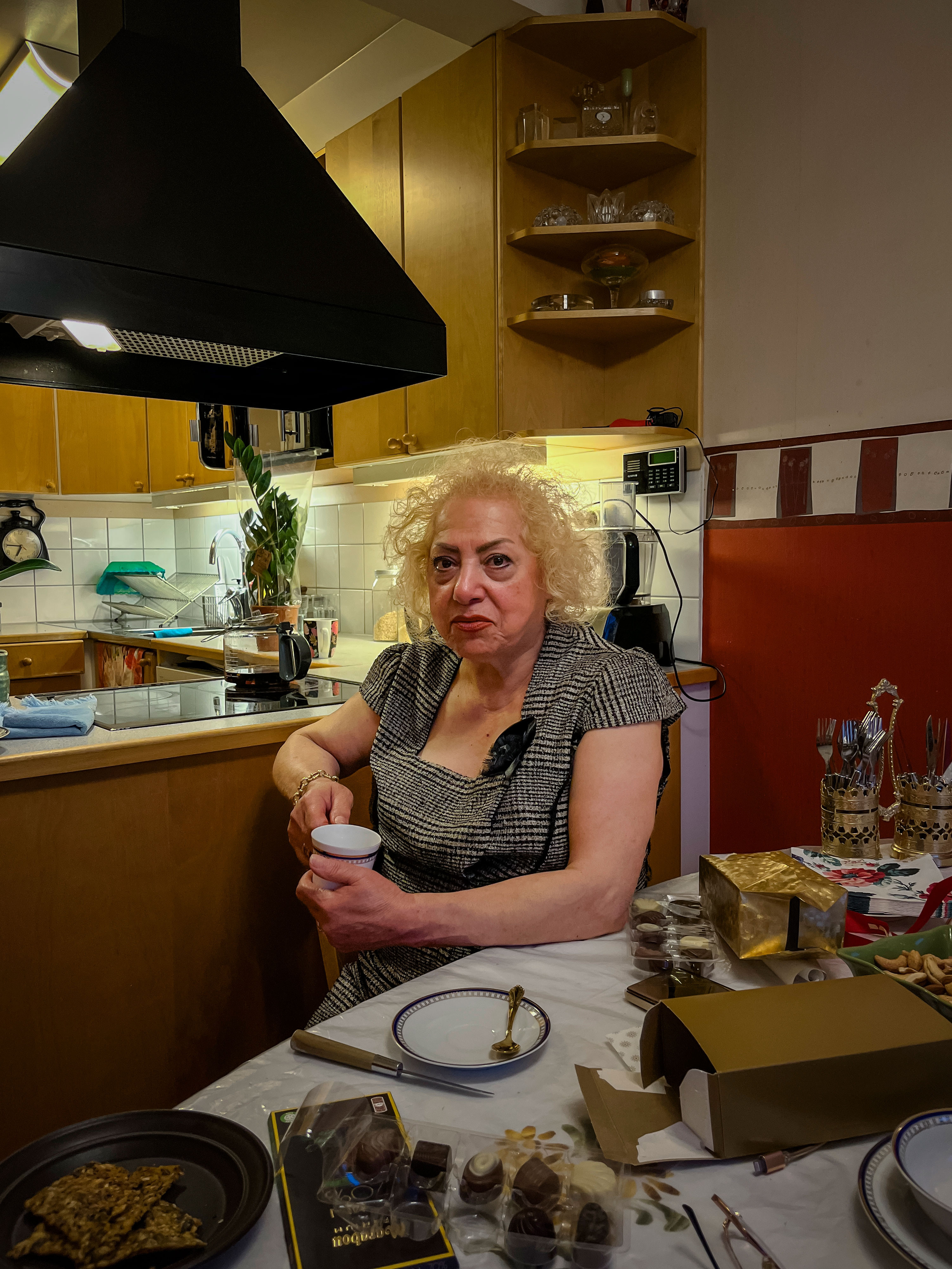 A woman sitting at a dining table holding a mug.