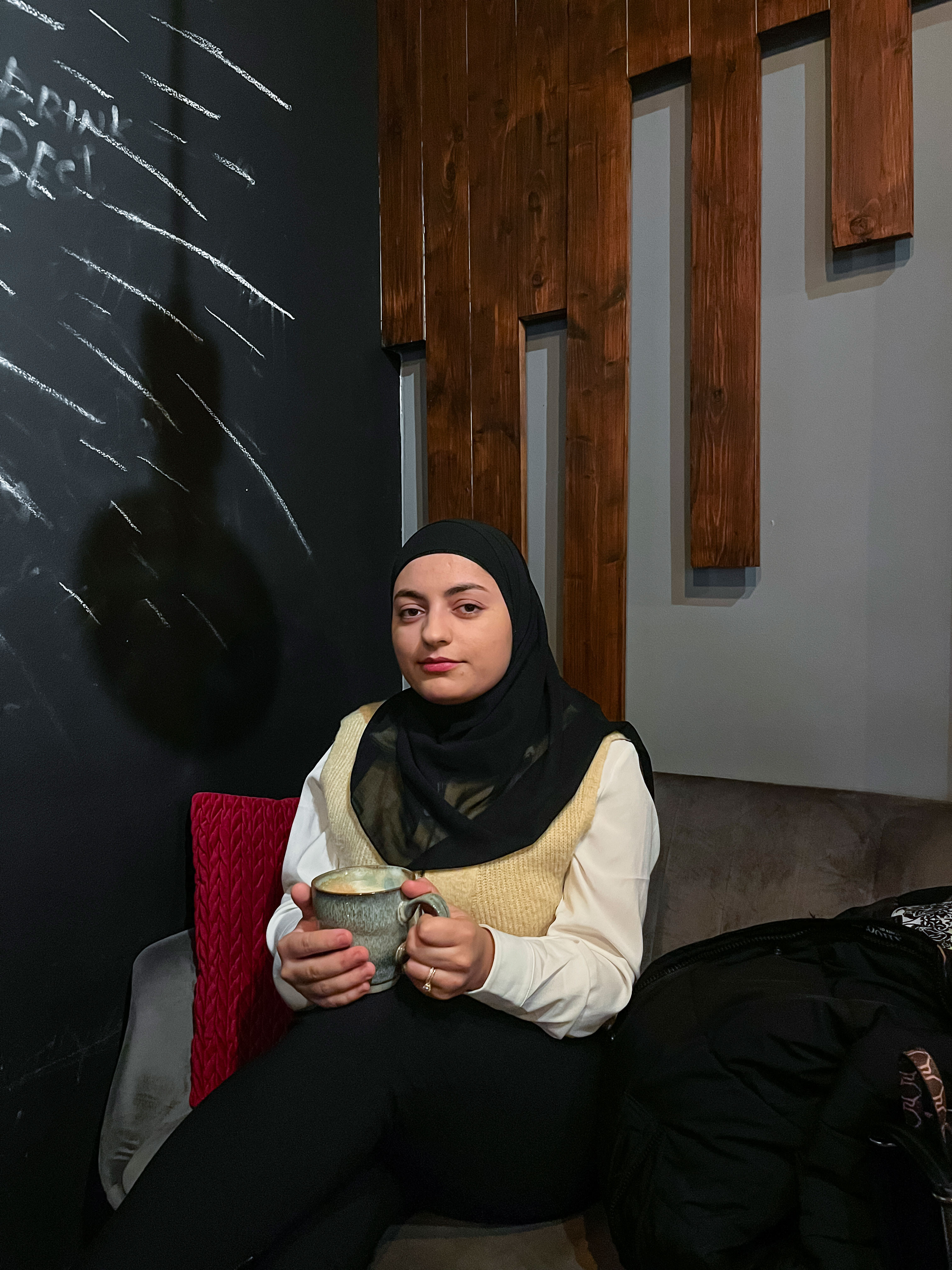 A woman sitting on a sofa holding a mug.