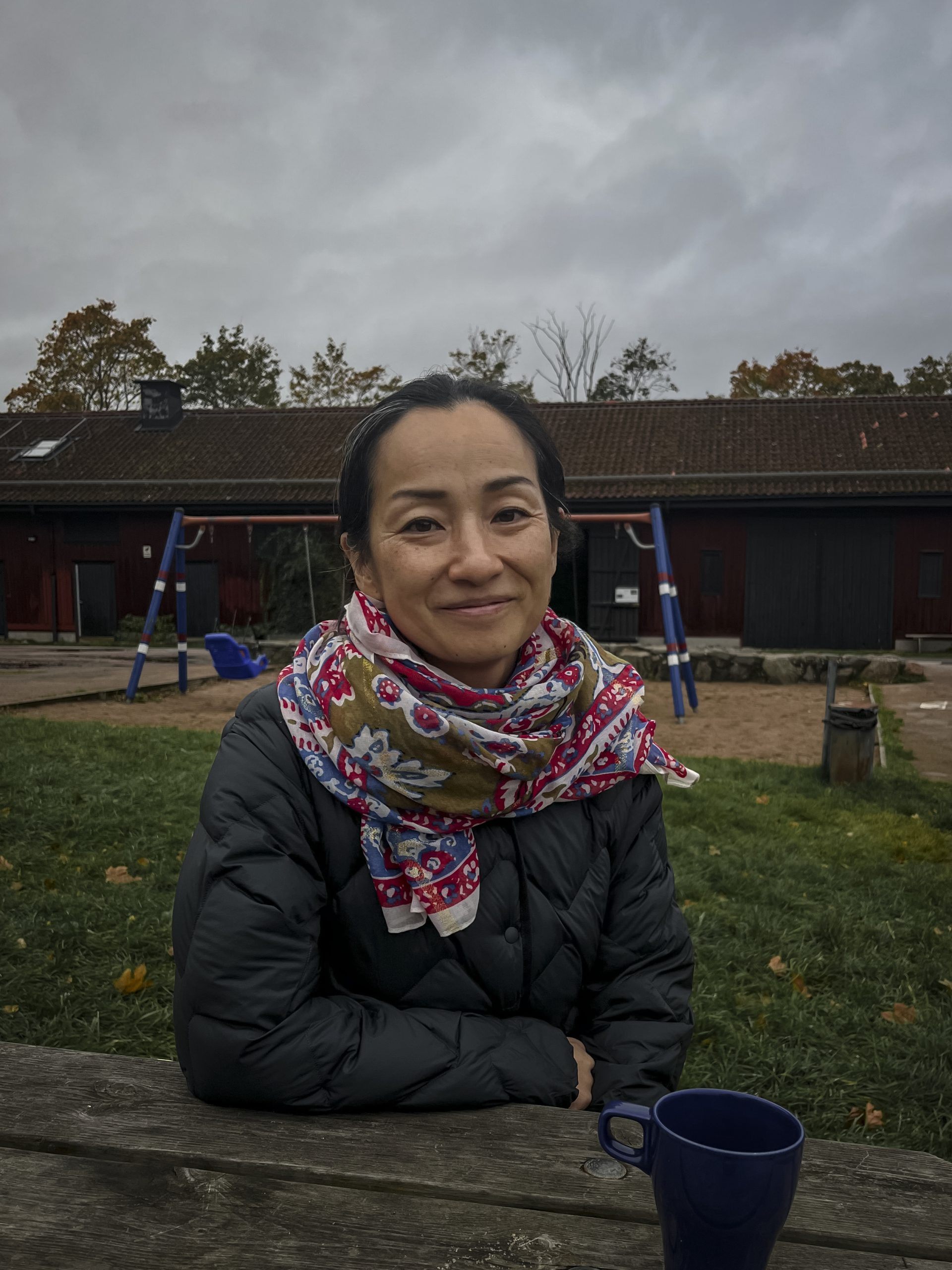 A woman sitting on a picnic table with her mug. 