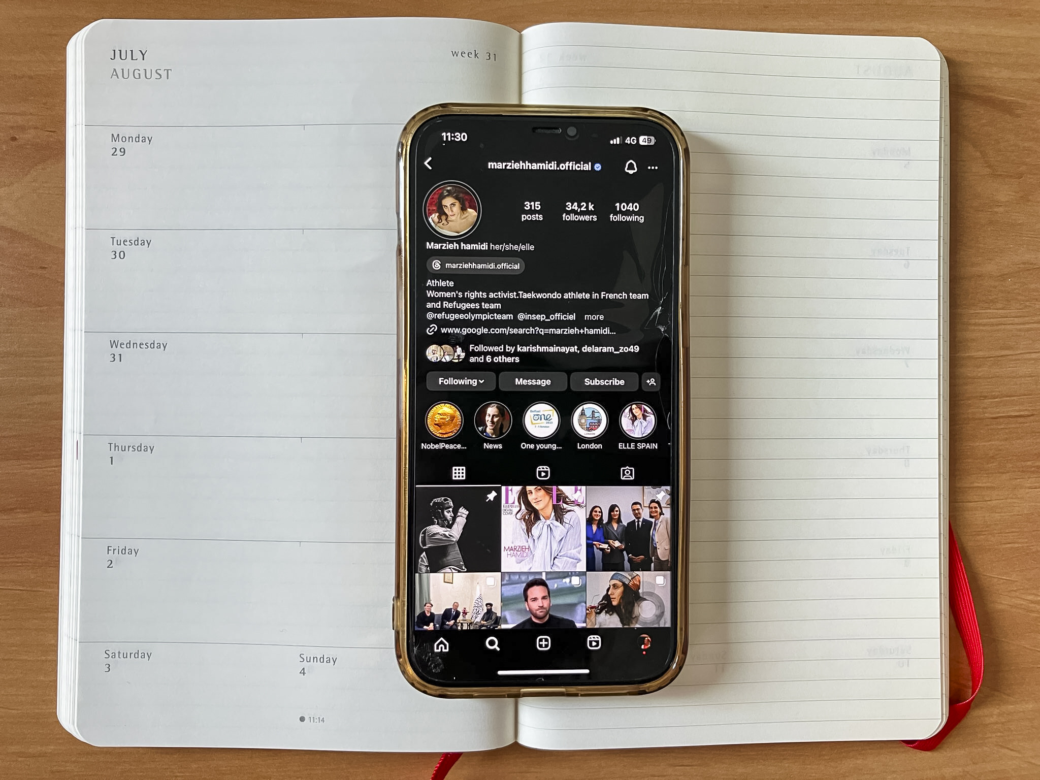 A book calendar with a mobile phone inside it. The instagram profile of Marzieh Hamidi is on the mobile's screen.